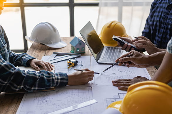 Construction workers a table with hard hats and plans